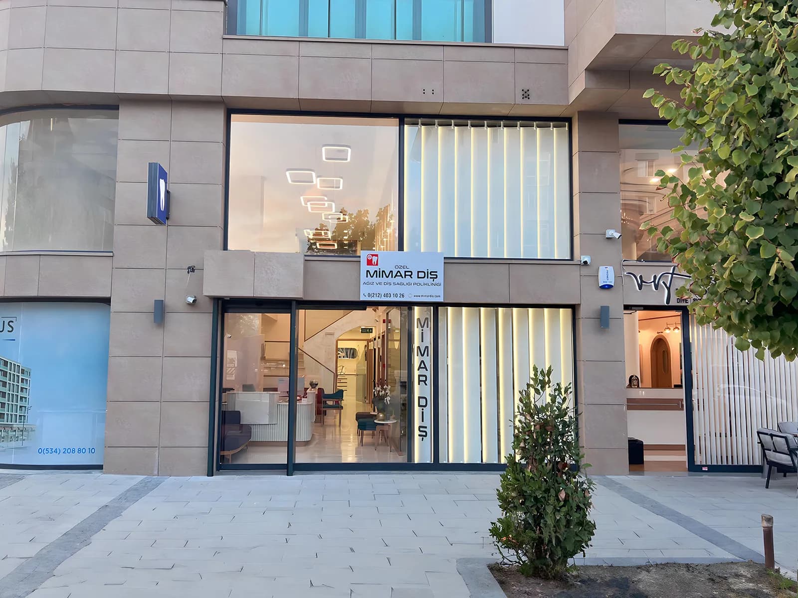 Kliniğin akşamüstü dış görünümü; aydınlatılmış giriş, tabela ve kaldırım