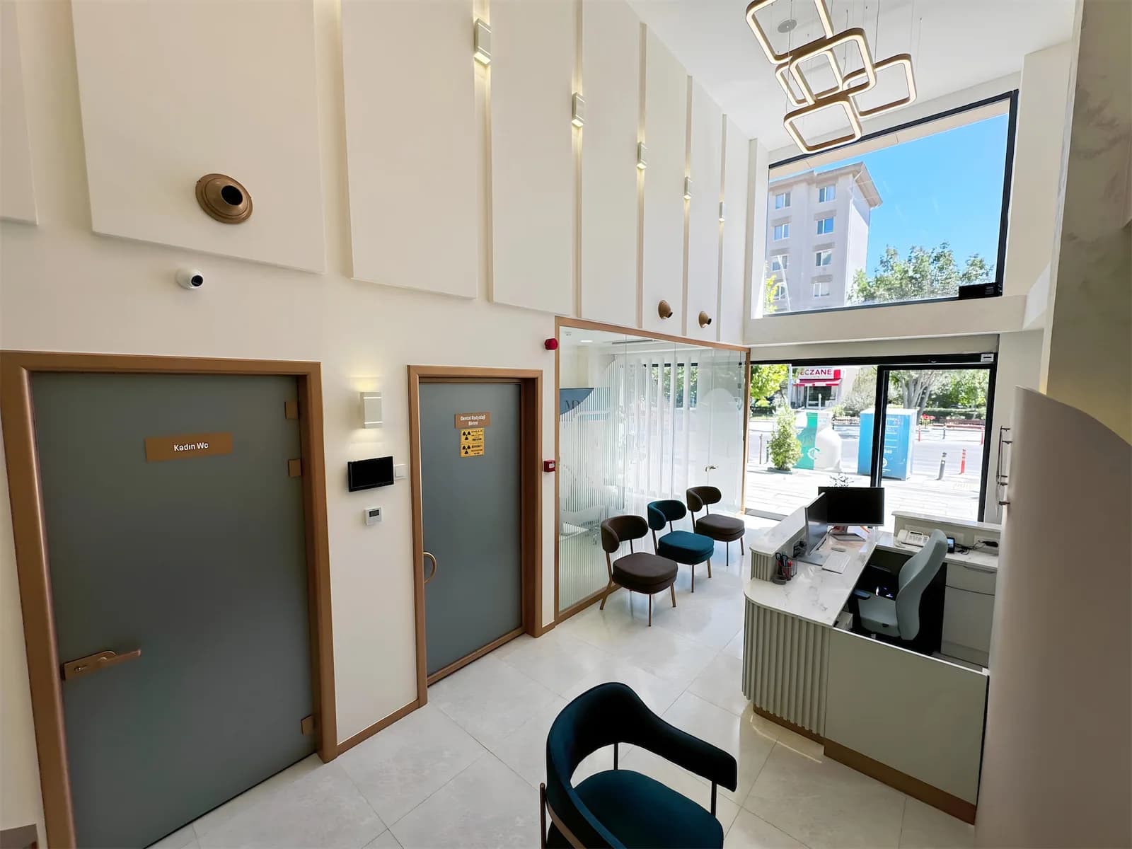 Klinik giriş holü; dental radyoloji birimi kapısı, resepsiyon masası ve cadde cephesine bakan pencere