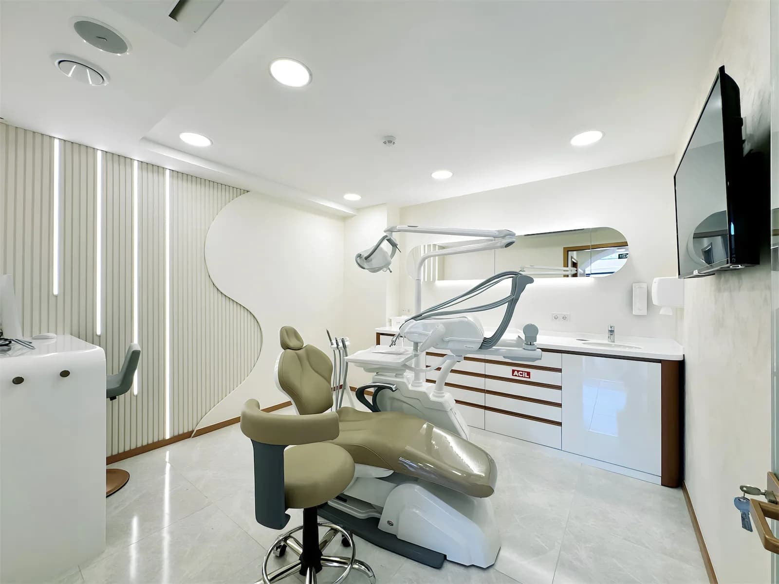Tedavi odası; diş ünitesi, oval aydınlatmalı ayna ve tezgâh üstü lavabo